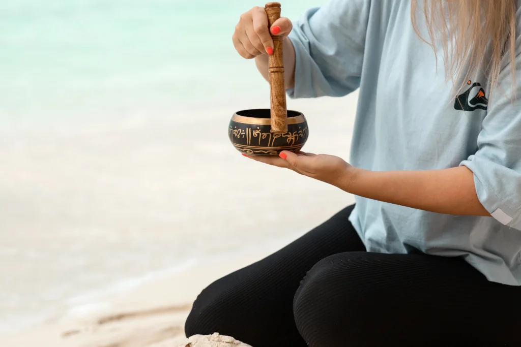 A young faceless woman playing on a singing Tibetan bowl. - Experience Healing Through Sound: Join Ciao Bella for a Transformative Gong Immersion in the Florida Keys