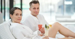 Young couple in bathrobes relaxing in spa center and having tropical cocktails - Unwrap Romance in Islamorada: A Holiday Spa Day for Two at Ciao Bella - Unwrap Romance in Islamorada: A Holiday Spa Day for Two at Ciao Bella - Ciao Bella Salon Spa Islamorada