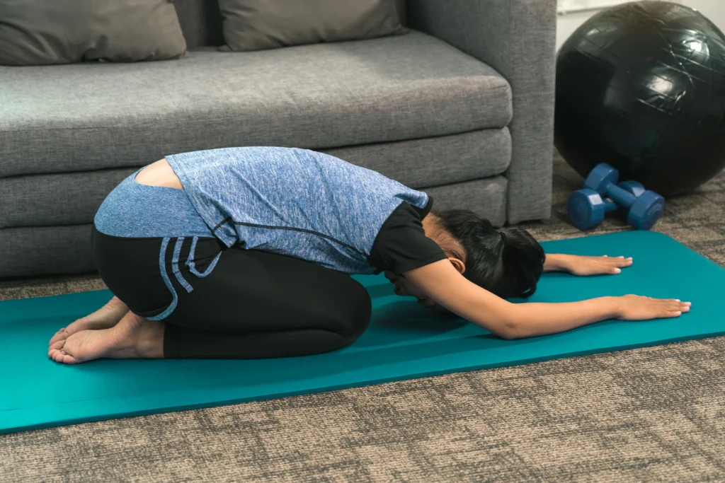 woman stretching on yoga mat at home